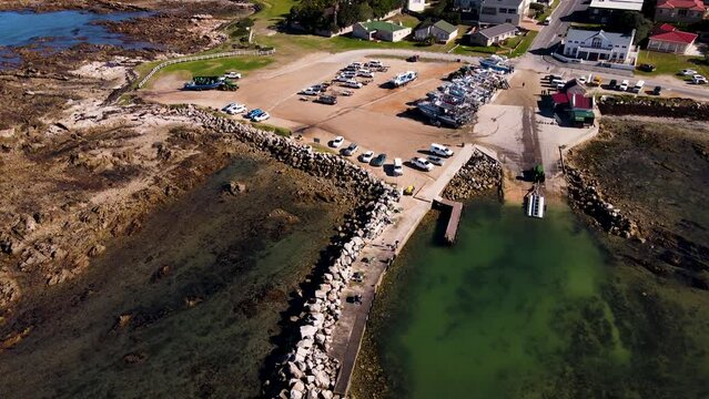 Aerial pullback reveals harbor where shark cage diving boats depart; Kleinbaai