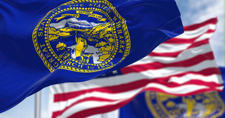 The Nebraska state flag waving along with the national flag of the United States of America - obrazy, fototapety, plakaty