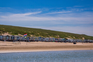 Fototapeta na wymiar View of beach huts on the beach in Egmnd aan Zee/Netherlands in front of a large dune
