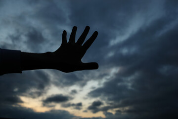 Young man hand silhouette and sunset with dark clouds. Photo was taken 1 June 2022 year, MSK time in Russia.
