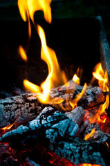 Fototapeta premium Flame of burning fire wood and smoldering charcoal close view abstract background
