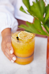 Cocktail de naranja en restaurante. Mujer sujetando vaso con la mano.