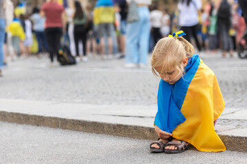 Ukraine Child with the flag of Ukraine is crying. Children refugees on Support Rally in Europe. Sadness longing hope. Anti war Protest in Europe.