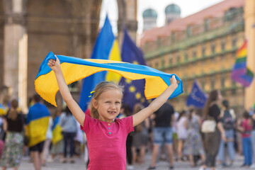 Ukraine flag in child hands at peaceful demonstration. Rally in support of Ukraine. Little girl...