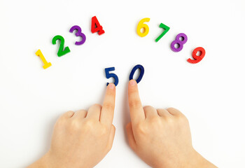 Children's hands move numbers on a white table. Learning colors and to count from zero to ten