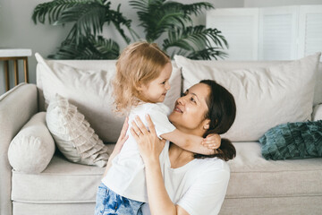 A mother gently hugs her four-year-old daughter.