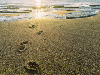 Bare footprints in the wet sand. Human footprints going into the ocean. 