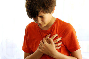 Teenager boy Caucasian holding his chest suffering from pain. Abnormal coronary artery course or...