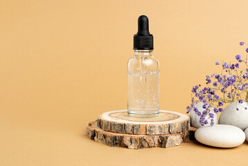 A wooden podium, stones, a sprig of gypsophila and a bottle with a pipette filled with hyaluronic acid, oil or essence. Body care concept, natural spa cosmetics