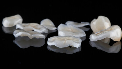 set of dental inlays made of fine ceramics for chewing teeth on black glass with reflection