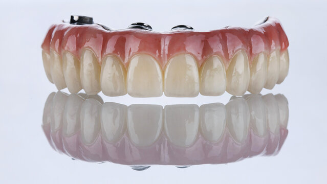 excellent upper jaw prosthesis made of zircon with artificial gum on white glass with reflection