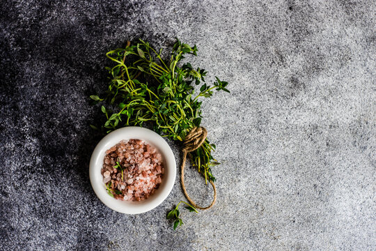 Overhead view of a bunch of fresh thyme next to a pot of pink Himalayan salt