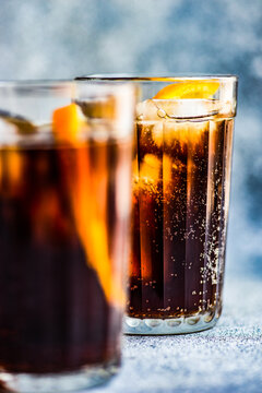 Close-up of two cola drinks with ice cubes and slices of fresh orange