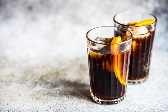 Close-up of two cola drinks with ice cubes and slices of fresh orange