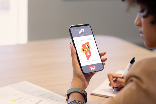 Biracial businesswoman working on report while researching nft on smart phone in office