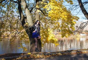 young girl stands near river in city park on autumn day