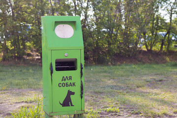 Green bin for dog poop. Responsible pet ownership and environmental protection. Background with copy space. Translation: for dogs