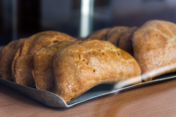 Baked empanadillas behind a bakery window.