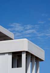 Low angle view of rectangle porch columns on terrace of white modern house building against blue sky in vertical frame