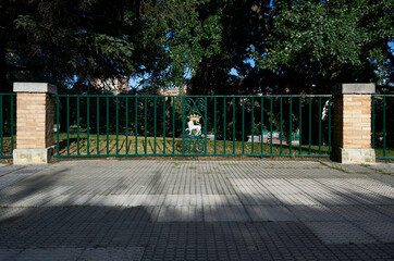 green metal fence between two brick pillars with the coat of arms of pamplona, which consists of a...