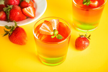 Glasses of tasty summer dessert layered colorful jelly with fresh strawberries