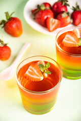 Glasses of tasty summer dessert layered colorful jelly with fresh strawberries
