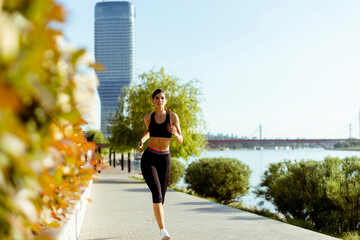 Young woman taking running exercise by the river promenade © BGStock72