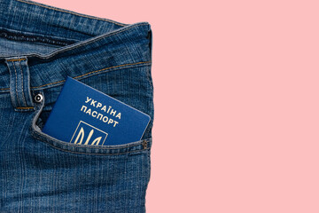 Passport in the pocket of denim pants isolate on a pink background with copy space. The concept of...