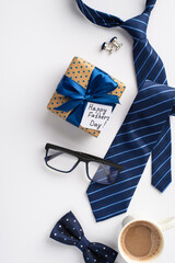 Father's Day concept. Top view vertical photo of polka dot giftbox with ribbon bow and postcard blue necktie bow-tie glasses cup of coffee and cufflinks on isolated white background