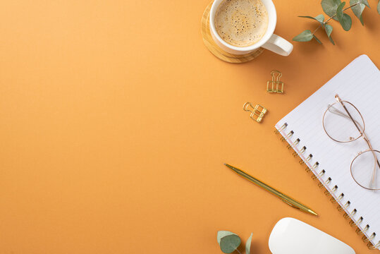 Business concept. Top view photo of workspace cup of hot drinking on wooden stand white computer mouse glasses notepad gold pen binder clips and eucalyptus on isolated orange background with copyspace