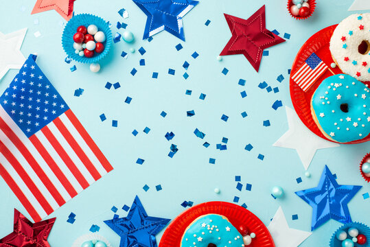 Fourth of July concept. Top view photo of national flags stars confetti paper backing molds with candies and plates with glazed donuts on isolated pastel blue background