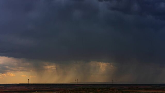 Molinos e&oacute;licos con nubes de tormenta en el atardecer timelapse