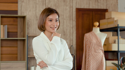 Young woman Asian Tailor Shop Owner, Close-up of the face of female mechanic who poses with her arms crossed behind her desk, Small business Professional Design clothes to sell online..