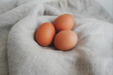 リネンに包まれた3つの茶色いにわとりの卵