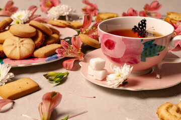 Assorted butter cookies on a pink hand-painted platter with natural flowers and served rooibos tea. 