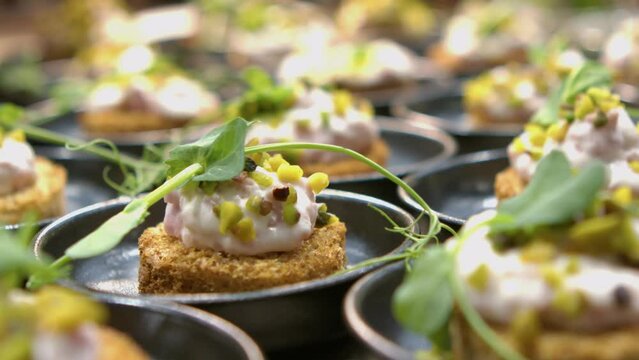 Close up of a canape with bread, ham mousse and chopped pistachios 