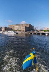 Stern flag on a commuting boat and the royal castle a sunny summer morning in Stockholm