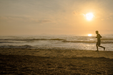 silhouette man run on beach with sunrise and sea background