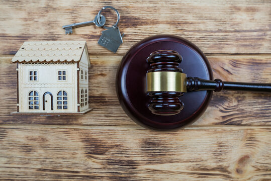  photo with wooden house, keys and judge's gavel on wooden background as symbol of mortgage or dilapidated housing being sold at auction or as symbol of legal dispute over division of real estate