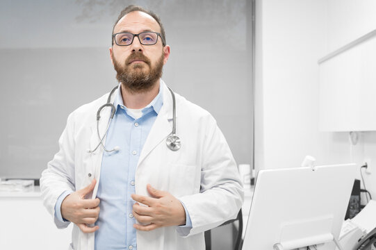 Middle age doctor man wearing white medical coat at the clinic with serious expression. High quality photo