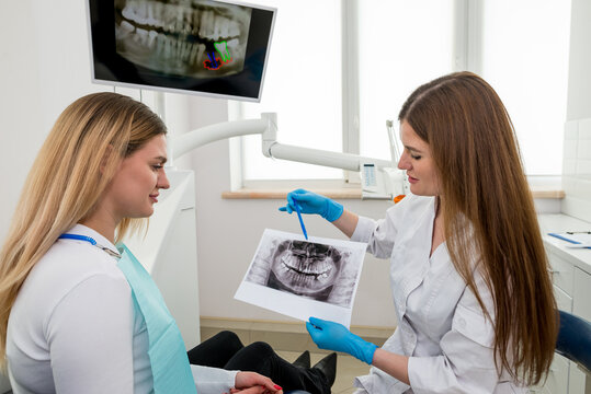 The dentist shows the x-ray image to the patient. People, medicine, dentistry, technology and healthcare concept.