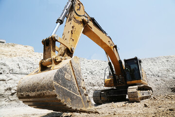 Excavator on earthworks at construction site. Backhoe on foundation work and road construction. Heavy machinery and construction equipment. Excavator under building