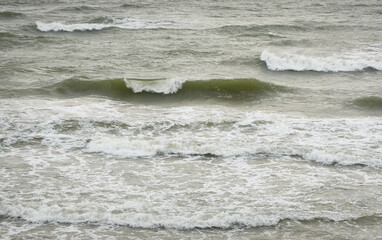 Sea foam, water surface texture, close-up. View from a sandy beach (sand dunes). Abstract natural...