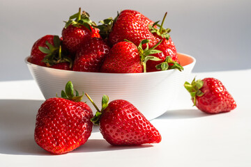 Ripe juicy strawberries in a white cup on a light (white-gray) background
