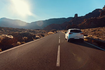 White car on the road in the Teide national park in the early morning. Surrounded by mountains and...
