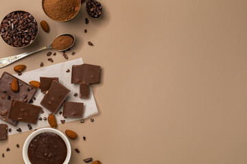 A variety of chocolate pieces and a whole bar with ingredients on a light background with copy space