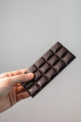 Man's hand holding a bar of chocolate on a white background