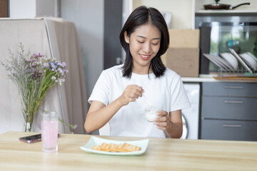 Obraz na płótnie Canvas Half-Japanese woman eats yoghurt with cereal for breakfast in room, Healthy food and digestive system maintenance, The most popular and easy to eat breakfast food.