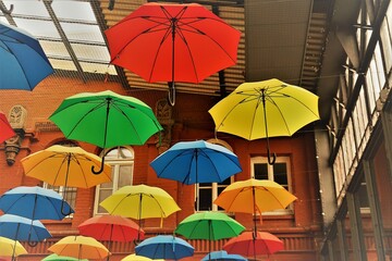 Fototapeta na wymiar Bunte Regenschirme unter hohem Gebäudedach 