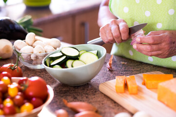 Close up on female hands cutting vegetables in the home kitchen. Fresh raw vegetables on the table